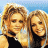 A 48x48 pixel animated buddy icon featuring two blonde women in a split-screen layout with green text on the right side.