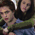 Two people embrace against a green background; one wears a blue shirt, the other dark hair and green clothing.