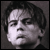 Pixelated grayscale portrait of a person with short dark hair, neutral expression, and visible facial features including eyes, nose, mouth, and ear against a solid gray background.
