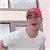 Pixelated static image of a person wearing a red cap and light-colored shirt against a blurred background with horizontal lines.