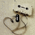 A static image of a beige cassette tape with black dots on top, positioned above a brown heart shape drawn in sand.