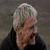 A person with light-colored hair transitions from a human face to a glowing blue skull