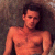 Pixelated image of a shirtless person with dark hair against a muted brown background, showing visible chest and shoulder details.