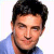 Static pixelated image of a person's face and upper shoulders in blue clothing against white background.