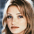 Pixelated close-up of a person with light brown hair and blue eyes, wearing a dark top against a blurred background.