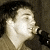 Pixelated image of a person holding a microphone next to text reading 'marc broussard .com' on brown background.