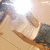 A pixelated image of a light-colored object with rounded edges on a wooden surface, partially obscured by bright glare and dark background elements.