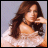 Static pixelated image of a person with long brown hair wearing a light-colored strapless top against a gray background.