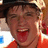 Pixelated image of a person in an orange shirt and cap with tongue out, on yellow background with red text.