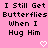 Pink background with black pixelated text repeating 'I Still Get Butterflies When I Hug Him' and two white heart symbols at bottom.