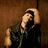 A pixelated image shows a person with light skin and dark hair leaning against a brown wall, while the right side displays bold text on red background.