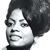 Pixelated grayscale portrait of a person with voluminous dark hair, neutral expression, and visible facial features including eyes, nose, and mouth.