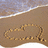 Pixelated beach scene with light blue sky, white wave crest, and brown sand forming a curved shoreline.