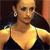 Pixelated close-up of a person with light skin wearing a dark sleeveless top and a silver earring, set against a dark background with warm tones.