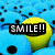 A pixelated yellow smiley face with black eyes and mouth appears among blue cartoon characters, displaying text overlays that change from 'SMILE!!' to 'its a...' then 'HAPPY DAY!!<3'.