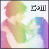 Two figures embrace in a pixelated style; the left figure wears a green shirt and the right figure has long blue hair. The text "C+m" appears in the top-right corner.