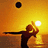 Pixelated image of a person silhouetted against a sunset, arms raised with one hand holding a basketball near the sun.
