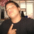 Pixelated image of a person with dark hair wearing a black shirt, making a finger-pointing gesture toward the camera.