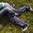 A pixelated figure in dark clothing lies on a grassy background with arms outstretched and legs bent at the knees.