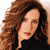 A pixelated close-up of a person with long brown hair wearing a black top against a light background.