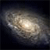 A static pixelated image of a spiral galaxy with a bright central core and fainter outer arms against a dark background.