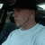 A person in a white shirt and dark cap sits inside a vehicle, with visible seatbelt and headrest, captured in a of four showing slight variations in head position