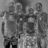 A grayscale pixelated image shows three figures in a row with indistinct facial features and clothing details.