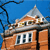 Pixelated image of a brick building with a domed roof against a blue sky, featuring a black curved line on the left side.