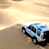 Animated car icon showing a white vehicle driving across sand dunes with visible text 'Coolbuddy.com' on the right side of the frame.