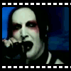 A person with pale skin, dark hair, and red eye makeup sings into a microphone against a blue background in a of six