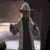 Animated sequence of a character in a brown robe holding a green lightsaber, transitioning from standing to crouching pose against a blurred background.
