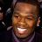 Pixelated close-up of a smiling person with dark skin tone wearing a purple garment against black background, captured as static single-frame image.