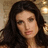 A static pixelated image of a person with long dark hair against a blurred background featuring warm tones and light sources.