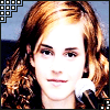 A pixelated close-up of a person with light brown curly hair holding a white microphone against a dark background.