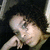 Pixelated image of a light-skinned figure with dark hair lying on a dark background, arms extended, wearing a light-colored garment.