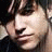 A pixelated close-up of a person's face with dark hair, showing two side-by-side views where the right view has visible text overlay.