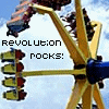 A yellow and blue amusement park ride with red and yellow seats against a light blue sky, featuring pixelated text reading "REVOLUTION ROCKS!" in the upper left.