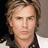 A pixelated portrait of a person with light brown hair and a white-collared dark shirt, displayed in a of four with varying background tones
