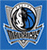 Pixelated blue background with a central circular emblem featuring silver and black tones, surrounded by stylized wing-like shapes.