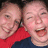 Two people in red and dark blue clothing pose closely together, one with arm around the other, on a pink background with text reading 'dear lehcar, lol. <8 ssej'.