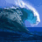 A static image shows a large blue ocean wave curling left with white foam, set against a clear sky.