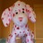 Pixelated static image of a light-colored dog with pink spots standing against a brown background.
