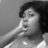 Black-and-white pixelated image of a person with dark hair resting hand near face, wearing light-colored top against gray background.