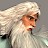 Pixelated image of a figure with long white hair and beard, wearing light-colored clothing against a muted background.