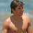Pixelated image of a shirtless person with short dark hair wearing a cap, standing against a blurred background.