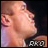 Pixelated close-up of a person's face in profile, with visible ear and neck against dark background; text 'AKO' appears below right.