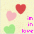 Pixelated image with three hearts and text reading 'in in love' on a light yellow background.
