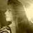 Pixelated grayscale image of a person with long hair in profile view, wearing a striped garment, against a gradient background.