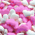 Pink and white cloud-shaped candies fill the frame with a soft, pastel color palette.