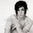 Pixelated grayscale image of a person with short dark hair wearing light-colored clothing against plain background.